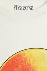 Remera de algodón color crudo, de corte amplio y mangas cortas. Estampado frontal con el logo de la banda de rock The Doors sobre un círculo con degradado de colores cálidos.