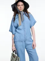 Camisa negra de manga corta confeccionada en denim liviano de tencel, de calce cuadrado y relajado. Presenta cierre frontal con tapeta escondida y costuras en color contraste.