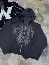 Campera de punto negra con capucha, cierre frontal completo y bolsillos estilo canguro. Presenta un diseño estampado de estilo gótico en la parte frontal y detalles con efecto desgastado en los bordes y puños.
