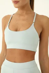 Top deportivo celeste de compresión media, con elástico invisible y tiras delgadas.