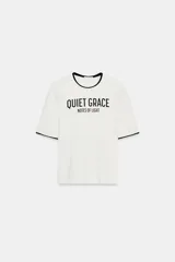 Camiseta de corte slim fit confeccionada en mezcla de algodón, con cuello redondo y manga corta. Presenta un diseño en color blanco con vivos negros en cuello y mangas, y un estampado frontal con el texto 'QUIET GRACE NOTES OF LIGHT'.