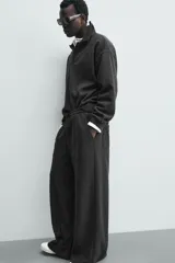 Pantalón de corte wide fit en tejido con acabado cepillado, color gris oscuro. Presenta cintura elástica con cordón ajustable, bolsillos delanteros y bolsillos traseros de plastrón.