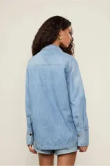 Camisa de jean celeste de corte clásico, con cuello, mangas largas, bolsillos frontales y cierre de botones.