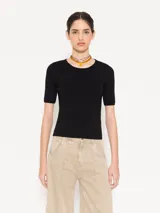 Top tejido color negro, de manga corta y calce al cuerpo. Presenta una abertura en la espalda que se ata al cuello.