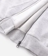 Buzo con capucha y cierre frontal, confeccionado en tejido fleece de algodón y poliéster. Presenta un diseño bicolor con cuerpo en gris melange y paneles laterales en las mangas de color negro, bolsillos frontales, y puños y ruedo en rib.