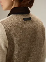 Chaqueta de lana hervida en color beige, con cierre frontal metálico y cuello camisero en contraste de color marrón oscuro. Presenta bolsillos frontales tipo parche y paneles laterales con textura diferenciada.