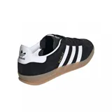 Zapatillas Adidas Gazelle Indoor negras de gamuza con las tres tiras blancas y suela color caramelo.