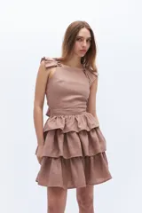 Falda corta de lino color rosado, con cintura marcada y tres volados superpuestos que generan volumen.