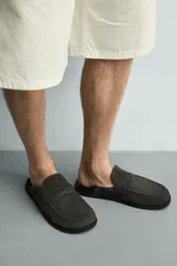 Zueco de hombre fabricado en piel con acabado serraje en color marrón claro. Presenta un diseño destalonado con detalle de antifaz en el empeine, horma redonda y suela plana a contraste.