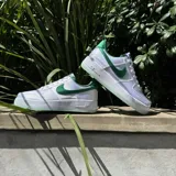 Championes Nike Air Force 1 07, con diseño de corte bajo en color blanco y detalles en verde esmeralda en el swoosh, talón y forro interior. Presentan una suela de goma con acabado traslúcido y tecnología Air.