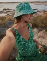 Gorro tipo bucket verde con estampado abstracto en blanco.