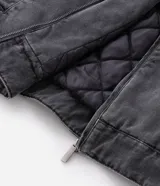 Chaqueta de denim color gris con acabado estonado, cierre frontal con cremallera, cuello camisero y manga larga. Presenta un estampado con la palabra 'OUTLAW' en tipografía gótica en el pecho y un bolsillo con cierre en la manga izquierda.