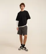 Bermuda masculina de corte slim, confeccionada en tejido de algodón con felpa. Presenta cintura elástica con cordón ajustable, bolsillos laterales y una pequeña etiqueta aplicada en el ruedo.