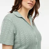 Camiseta de punto calado color celeste con cuello polo y cierre frontal con botones.