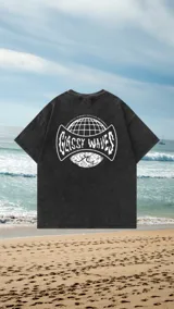 Remerón de manga corta en color negro con efecto lavado (acid wash). Presenta un gran estampado gráfico en la espalda con diseño circular, globo terráqueo y la inscripción 'Glassy Waves'.