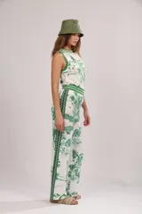 Pantalón de algodón blanco con estampado de palmeras, camellos y aves en color verde.