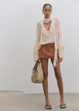 Short tipo falda pantalón de tiro bajo, color tostado, con diseño de tablas y bolsillos laterales.