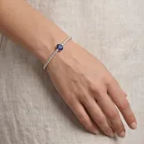 Pulsera de plata 925 tipo tenis, con una hilera de circonias blancas y un dije central de circonia azul en forma ovalada.