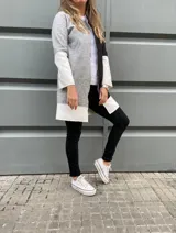 Tapado de paño gris con mangas y ruedo en cuero sintético blanco y detalle en negro en el frente.