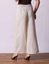 Pantalón largo de poliéster color beige con rayas verticales, pretina ancha elastizada en punto smock y pierna ancha.