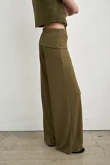 Pantalón palazzo negro de tiro alto con cintura ancha plegable, confeccionado en tela de punto fruncida y corte holgado.