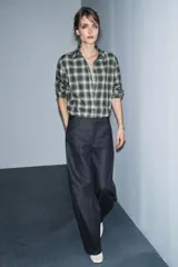 Camisa de corte oversize confeccionada en algodón, con estampado de cuadros en tonos verde, negro y blanco. Presenta cuello solapa, cierre frontal con botones, manga larga con puños y bajo asimétrico.