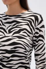 Sweater de punto con estampado floral en tonos rosados y marrones sobre base color crema, de cuello redondo y manga larga.