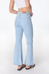 Jean azul claro de corte flare con aberturas en los tobillos y detalles rotos en las rodillas y muslos.