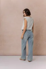 Jean wide leg de tiro medio-alto en denim azul medio con lavado desgastado. Presenta diseño de cinco bolsillos, cierre con botón y cremallera, y pierna amplia de caída recta.