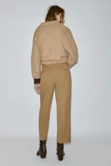 Pantalón de tiro medio con pinzas delanteras y pernera recta. Cuenta con bolsillos frontales, falsos bolsillos traseros de vivo y cierre frontal con cremallera, botón interior y ganchos.