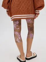 Calza deportiva 3/4 de tiro alto, confeccionada en lycra con un diseño estampado abstracto en tonos tierra, verdes y rosados.