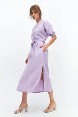 Vestido midi color coral confeccionado en lino. Tiene corte recto, mangas abullonadas con detalle de tablas en el puño, tajos laterales y lazo en la cintura.