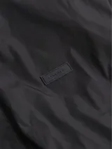 Chaleco negro Calvin Klein con cuello alto, cierre de cremallera, bolsillos laterales, bajo con cordón ajustable y logo tonal en el pecho.