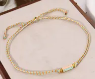 Set de collares cortos con cordones trenzados de múltiples colores y dijes cilíndricos con inscripciones y detalles esmaltados.