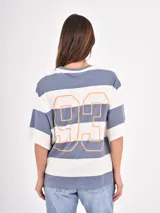 Remera de corte holgado con diseño de rayas horizontales anchas en tonos azul y blanco, cuello redondo y mangas cortas.