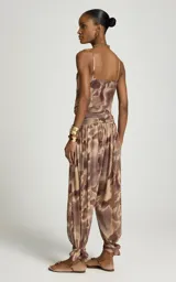 Pantalon balloon de tul con estampado abstracto en tonos marrones y beige, pretina ancha fruncida, forro interior y bajos ajustados con tiras para atar en los tobillos.