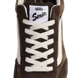 Championes Vans modelo Super Lowpro, de perfil bajo, confeccionados en gamuza marrón con detalles en cuero blanco. Presentan la clásica franja lateral de la marca, cordones blancos y suela de goma dentada.
