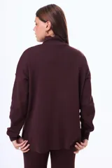 Buzo tejido de punto color negro, con cuello alto, manga larga y corte holgado con aberturas laterales en el ruedo.