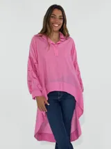 Blusa color coral con cuello camisero, mangas largas con detalles de calado y bajo irregular.