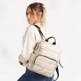 Mochila color beige con diseño acolchado en forma de rombos. Tiene un bolsillo frontal con cierre, un bolsillo lateral abierto y un compartimento principal con cierre. Las correas son ajustables y tiene un asa superior.