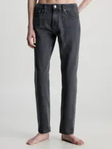 Jeans de denim rígido de algodón, color negro descolorido, con talle medio a bajo, pierna recta y bragueta con cremallera.