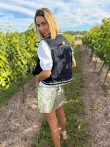 Chaleco de jean negro con apliques de caracoles cosidos a mano en los bordes.