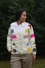 Cardigan de lana merino tejida a mano con dos agujas, color blanco con diseño de figuras geométricas en tonos multicolor y cierre frontal con botones de madera.