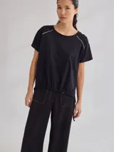 Remera negra de algodón con mangas cortas con detalle de calado y bordado en los hombros y mangas. Corte recto con cintura ajustable con cordón.
