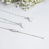 Conjunto de cadena fina y medalla circular de plata 925, con grabado lineal de figuras infantiles en el frente.