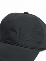 Gorro con visera color beige, con logo bordado de una montaña en el frente.