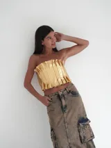 Top strapless de cuero metalizado color dorado, con diseño de tablones verticales en el frente que aportan estructura y elástico en la espalda para un ajuste cómodo.