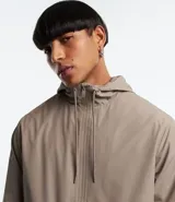 Campera rompevientos color verde oliva con capucha ajustable con cordón, cierre frontal con cremallera, bolsillos laterales con cremallera, puños con elástico y forro interior. Ligera y versátil, ideal para proteger del viento y la lluvia ligera.