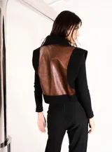 Chaleco marrón con cierre frontal, paneles de cuero en el frente y espalda de tejido de punto negro.