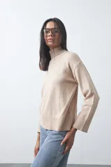 Polera de tejido liviano color negro con cuello alto y silueta relajada. Presenta mangas largas con puños ajustados y recortes laterales que aportan estructura al diseño.